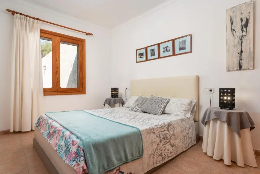 A bedroom with a bed, bedside tables, and a window with curtains.