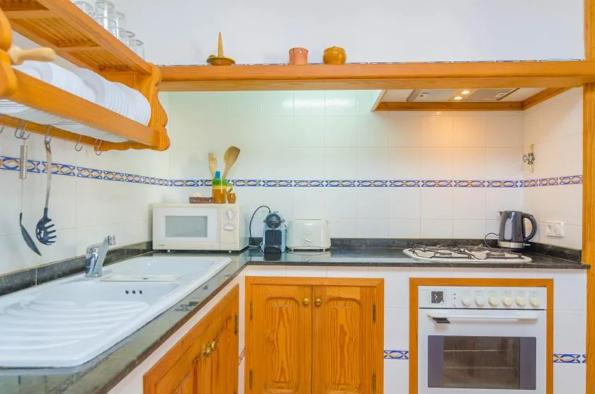 A compact kitchen with wooden cabinets, a sink, and a built-in oven.