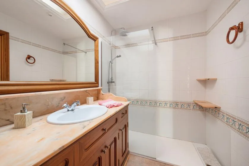 A tiled bathroom with a vanity, large mirror, and shower.