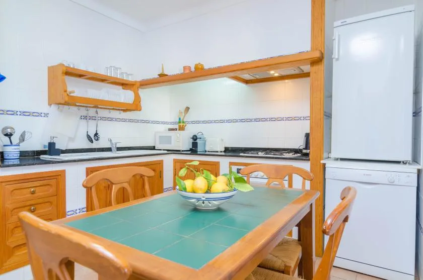A kitchen dining area with a green-tiled table and wooden seating.