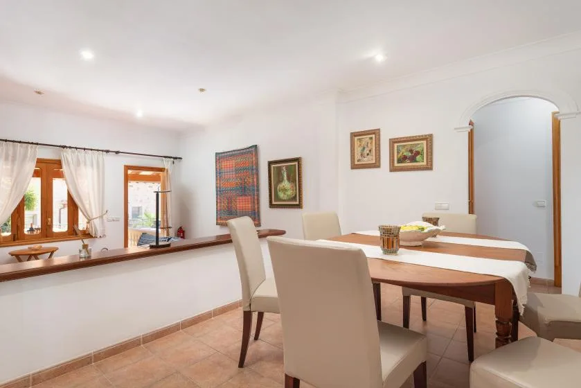 A dining area with a long table, upholstered seating, and framed artwork.
