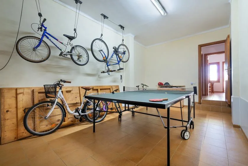 A recreation room with a ping-pong table and bicycles stored along the wall.