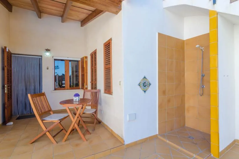A tiled room combines a small wooden dining set with an open shower area.