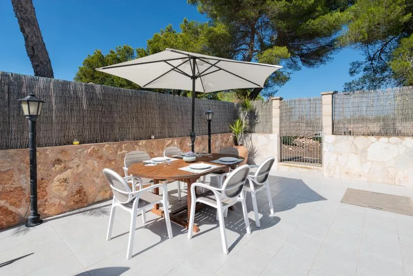 An outdoor dining area with a table and chairs beneath a large umbrella.