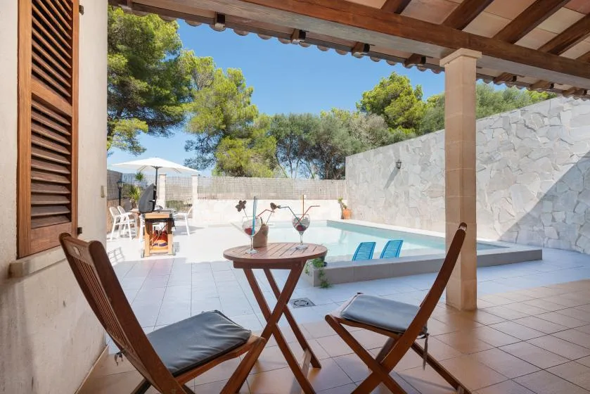 A covered patio overlooks a small pool, with outdoor seating in the foreground.