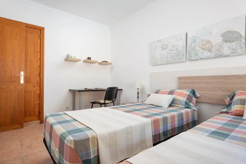 A bedroom with two beds dressed in colorful plaid bedding.
