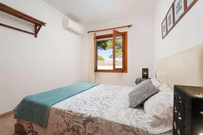 A bedroom with a bed, patterned bedding, and a window.