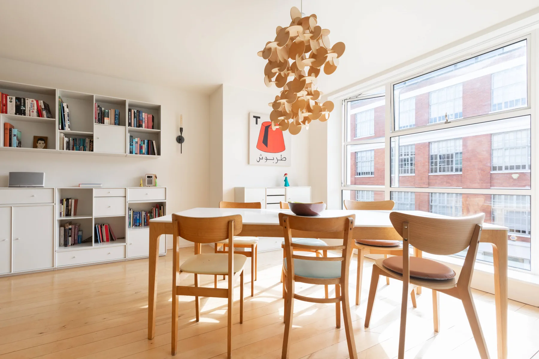 Un comedor luminoso con una mesa de madera y sillas junto a grandes ventanas.