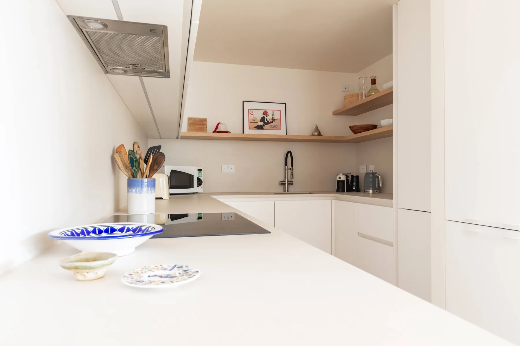 Una cocina luminosa con encimera blanca, placa de cocción y fregadero.