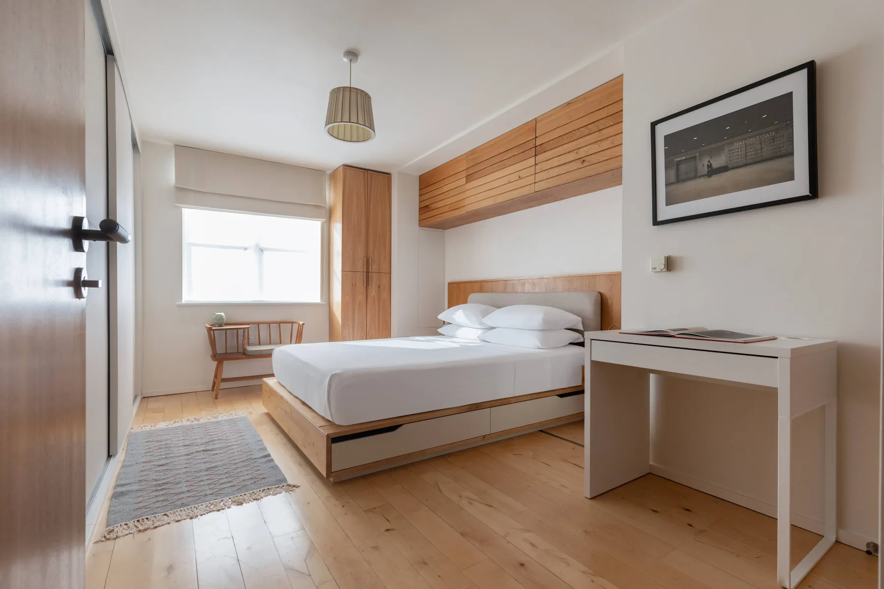 Un dormitorio luminoso con una cama, un escritorio y una ventana.