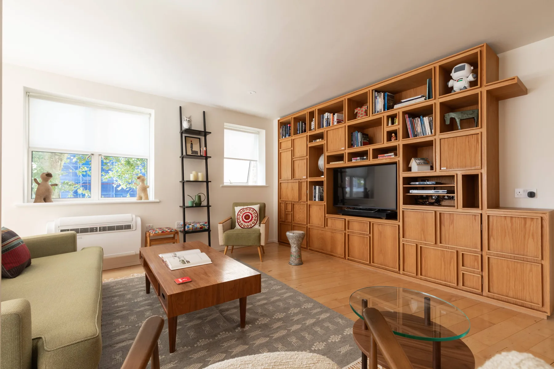 Una sala de estar con estanterías de madera, un televisor y asientos.