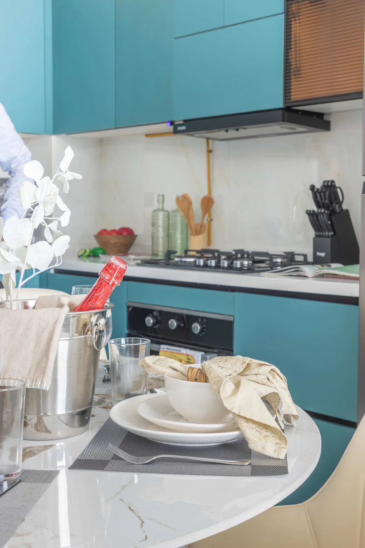 A modern kitchen with teal cabinets and a gas cooktop.