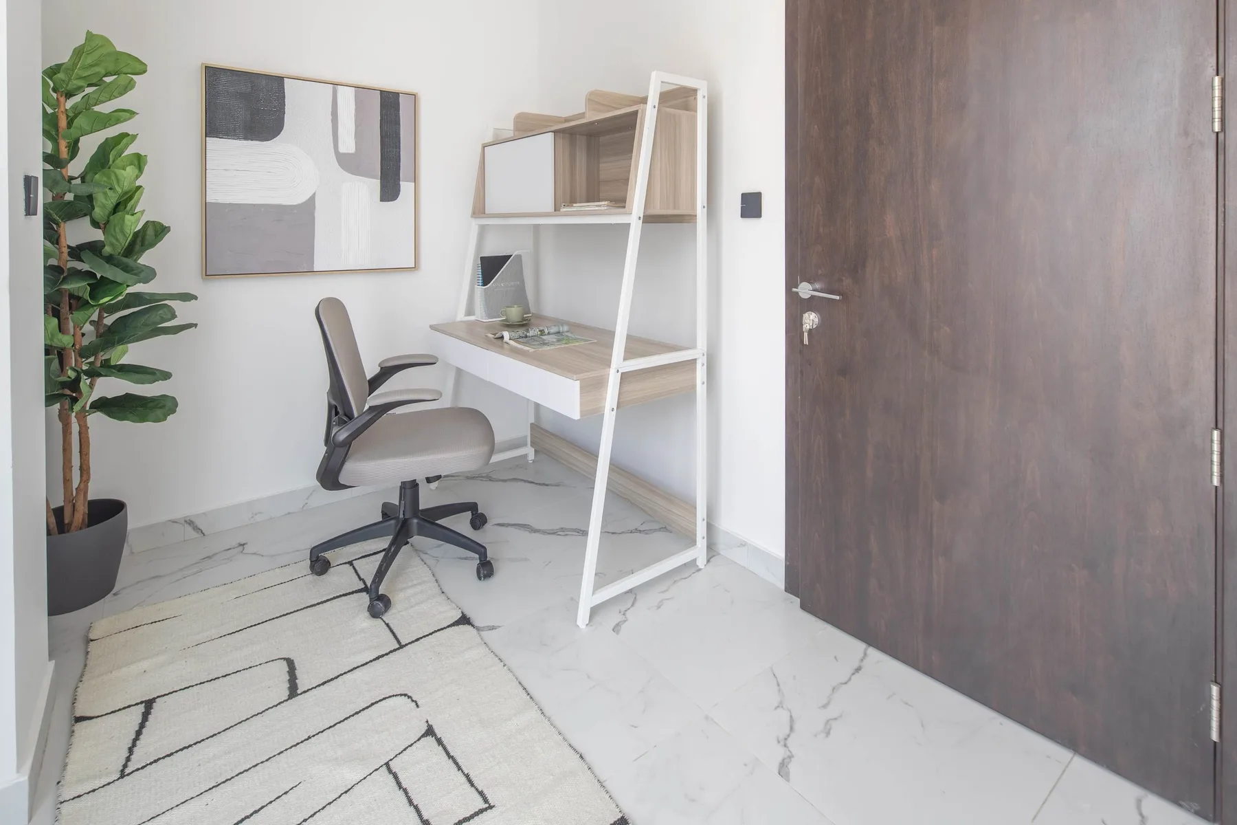 A compact workspace with a desk and office chair beside a large potted plant.