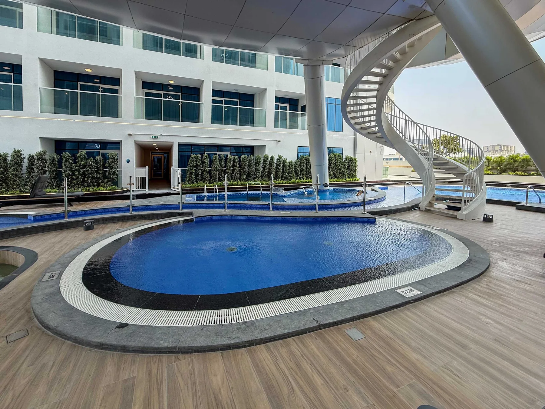 An outdoor pool area with a curved water slide beside a modern building.