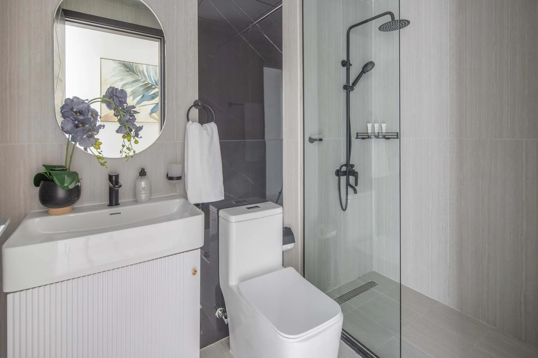 A modern bathroom with a sink, toilet, and glass-enclosed shower.