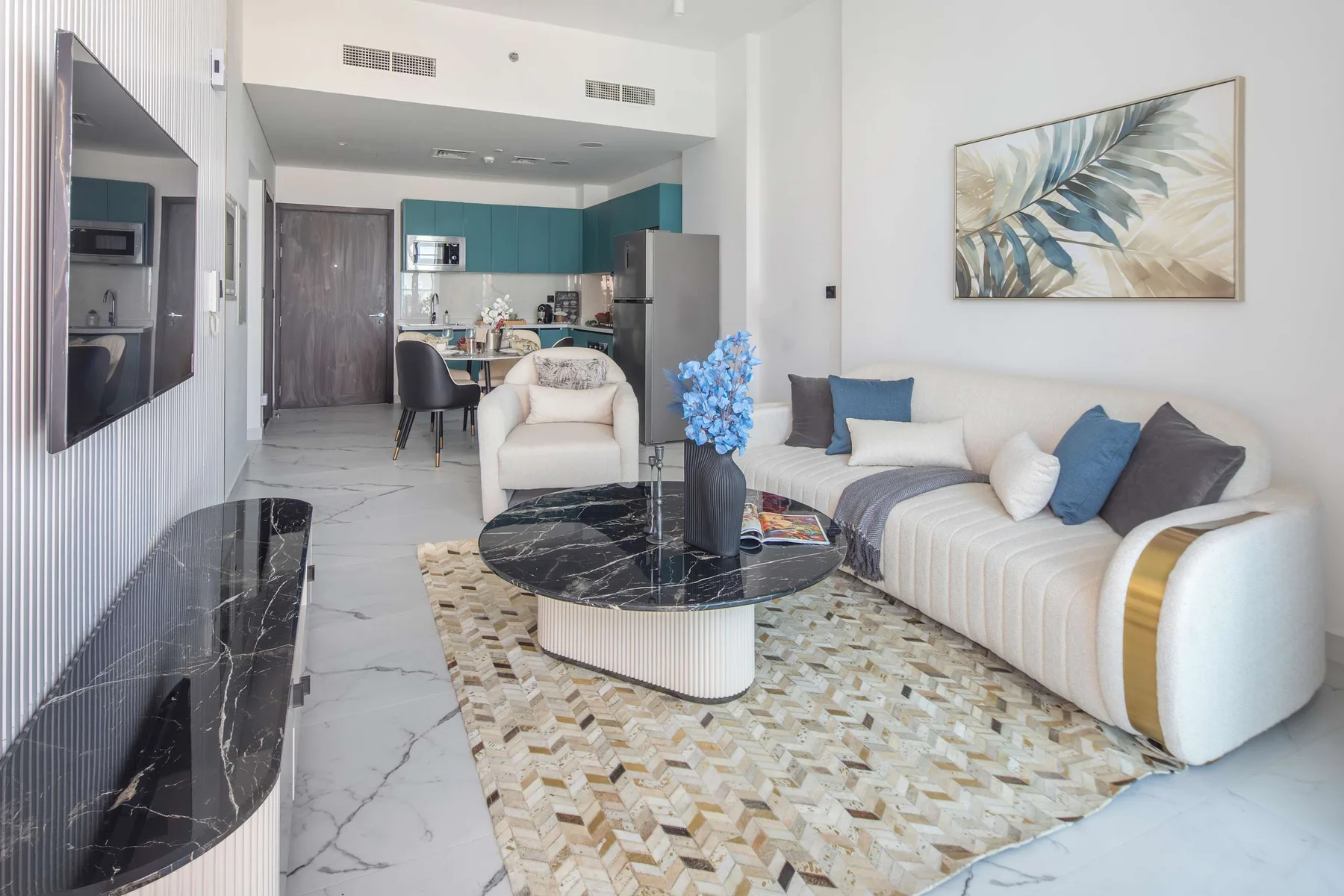 A bright living room with seating, a coffee table, and an open kitchen.