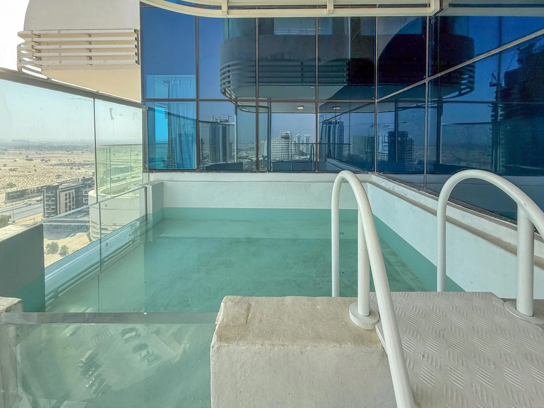 A small swimming pool sits beside floor-to-ceiling windows overlooking the city.