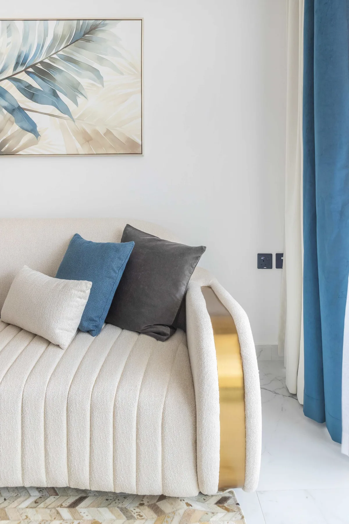 A bright living area features a cream sofa with blue and gray cushions.