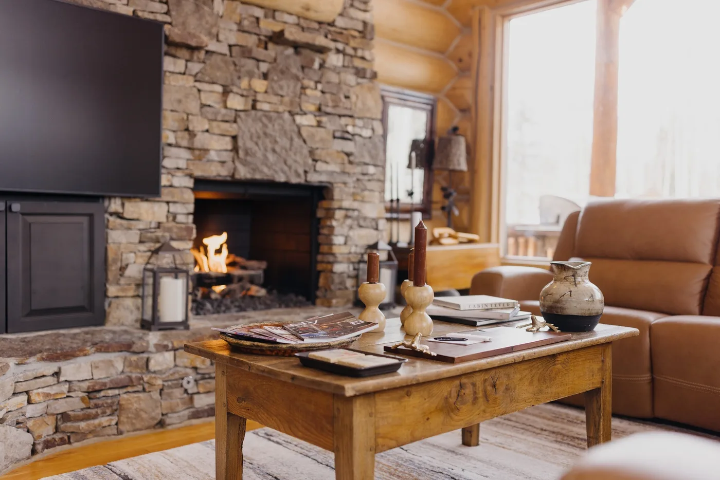 Una sala de estar rústica con chimenea de piedra, mesa de centro de madera y asientos de cuero.