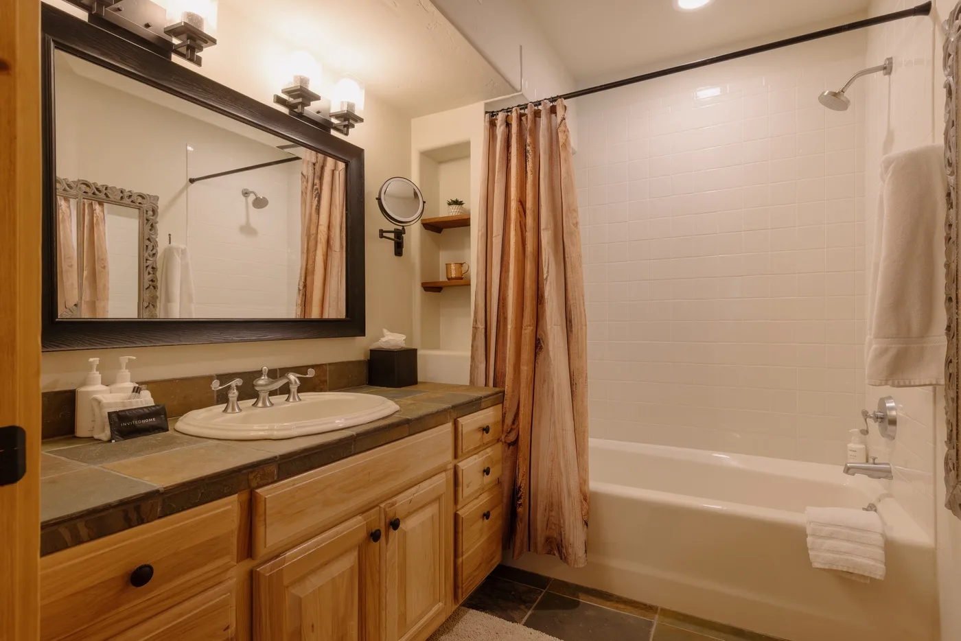 Un baño con lavabo, espejo y bañera con cortina.