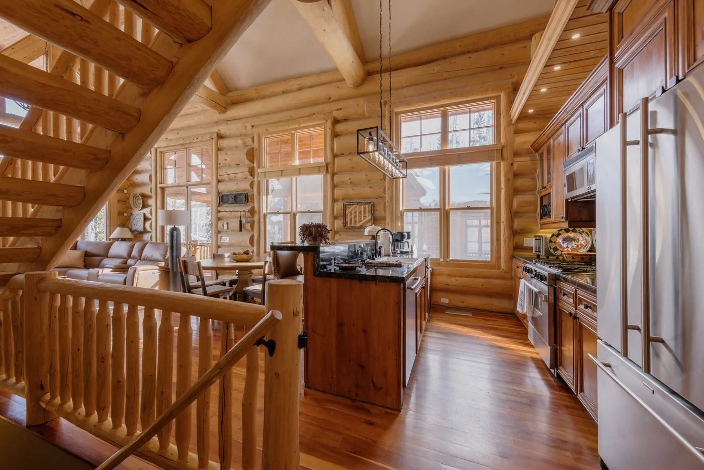 Una cálida cocina de madera con isla central, comedor y grandes ventanas.