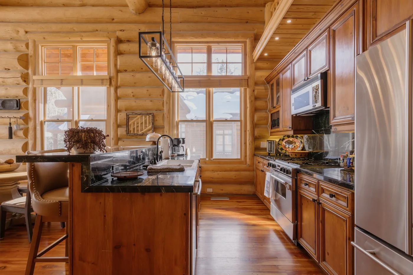Una cocina revestida de madera, con una isla central y ventanas grandes.