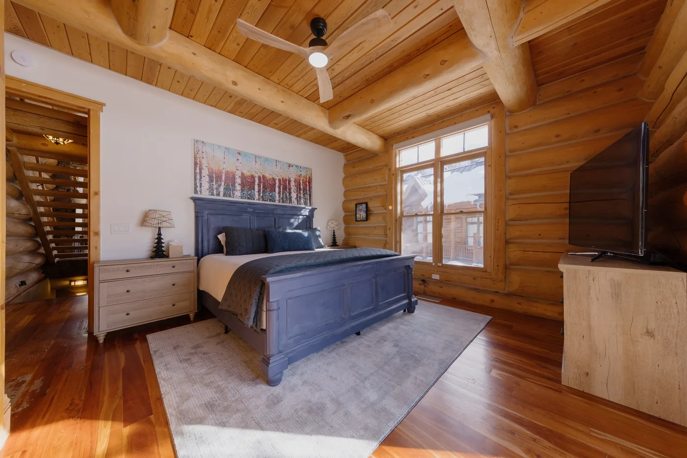 Un dormitorio con una cama de madera, una mesita de noche y ventanas grandes.