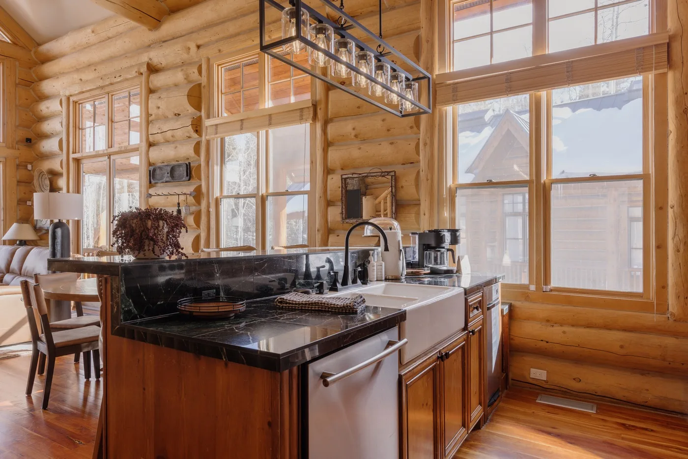 Una cocina de troncos con una isla central y grandes ventanas.