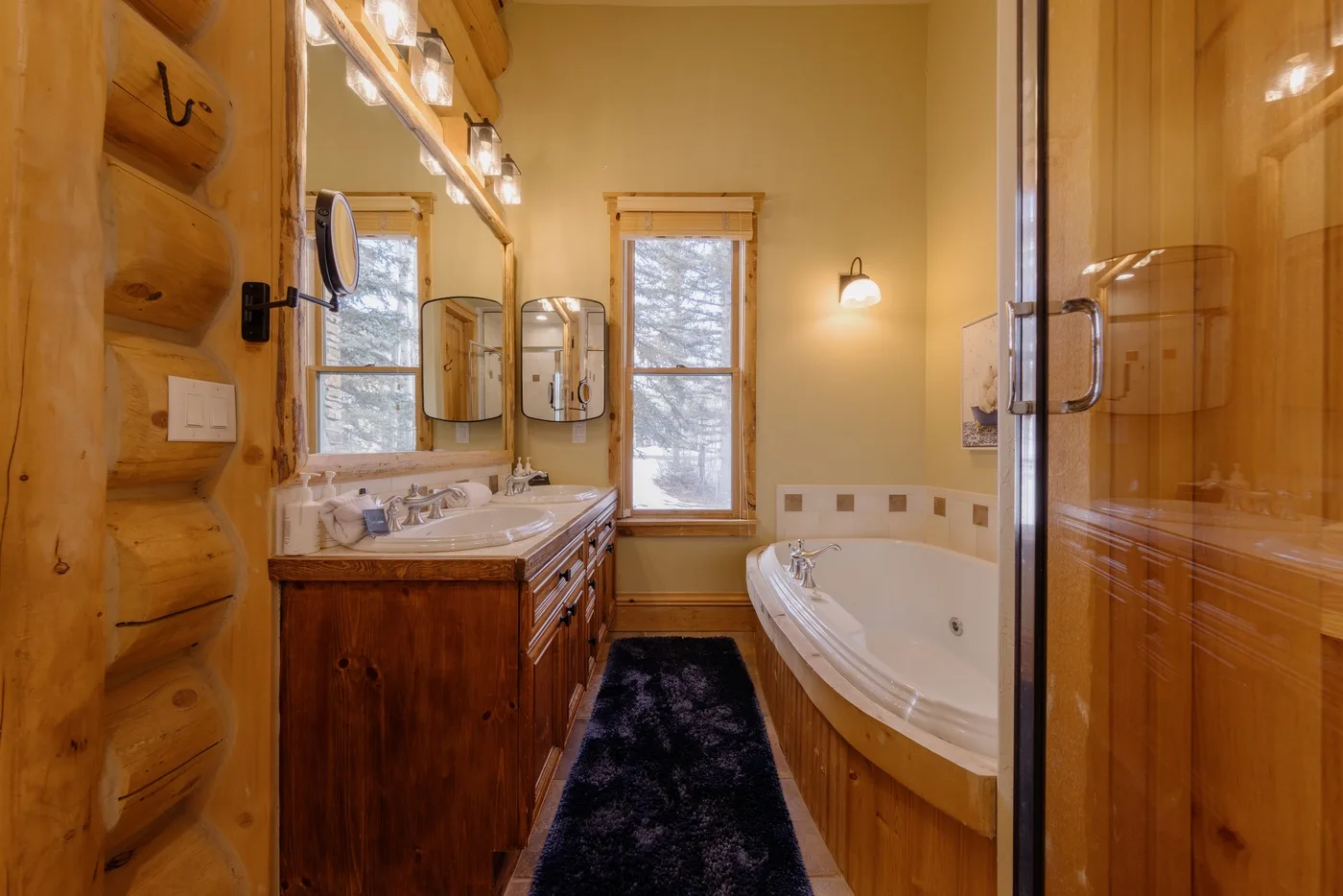 Un baño con tocador de madera, espejo grande y bañera esquinera.