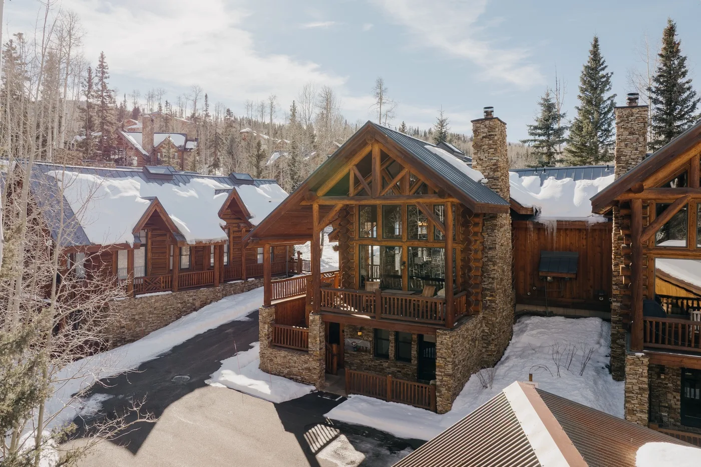 Edificios de cabañas cubiertos de nieve, con balcones de madera entre los árboles.