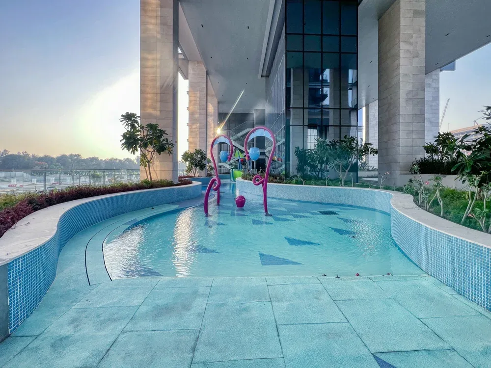 Una piscina poco profunda está junto a un edificio alto con fachada de vidrio.