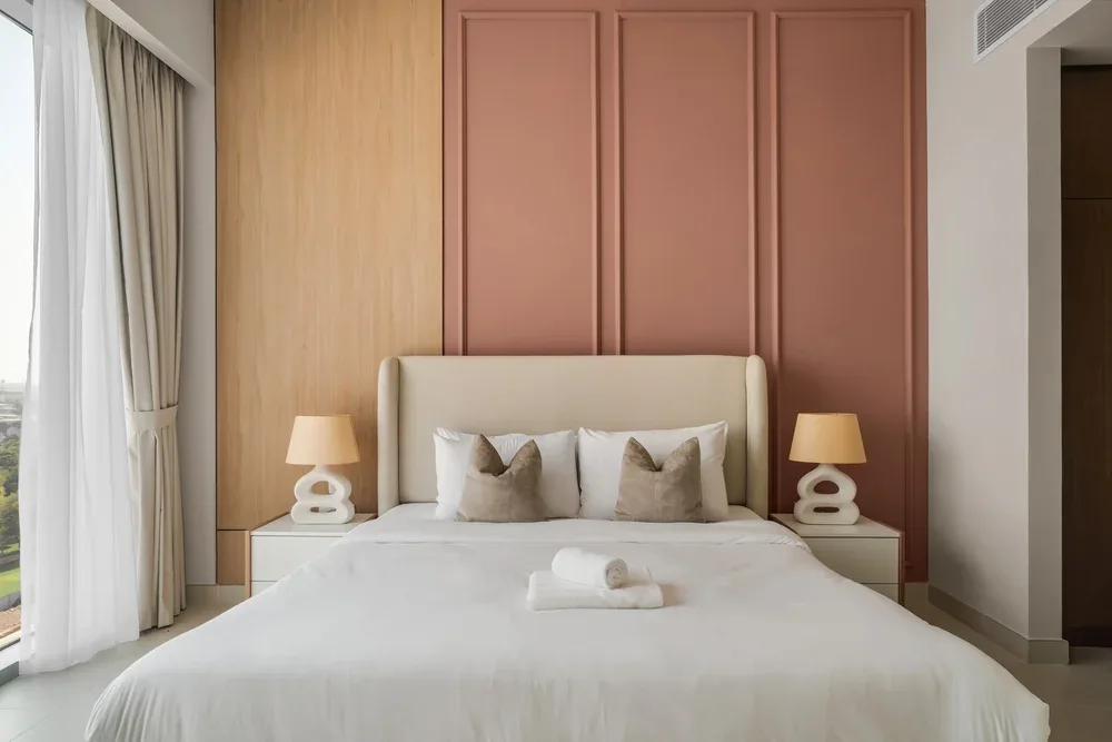 A bedroom with a neatly made bed and matching bedside lamps.