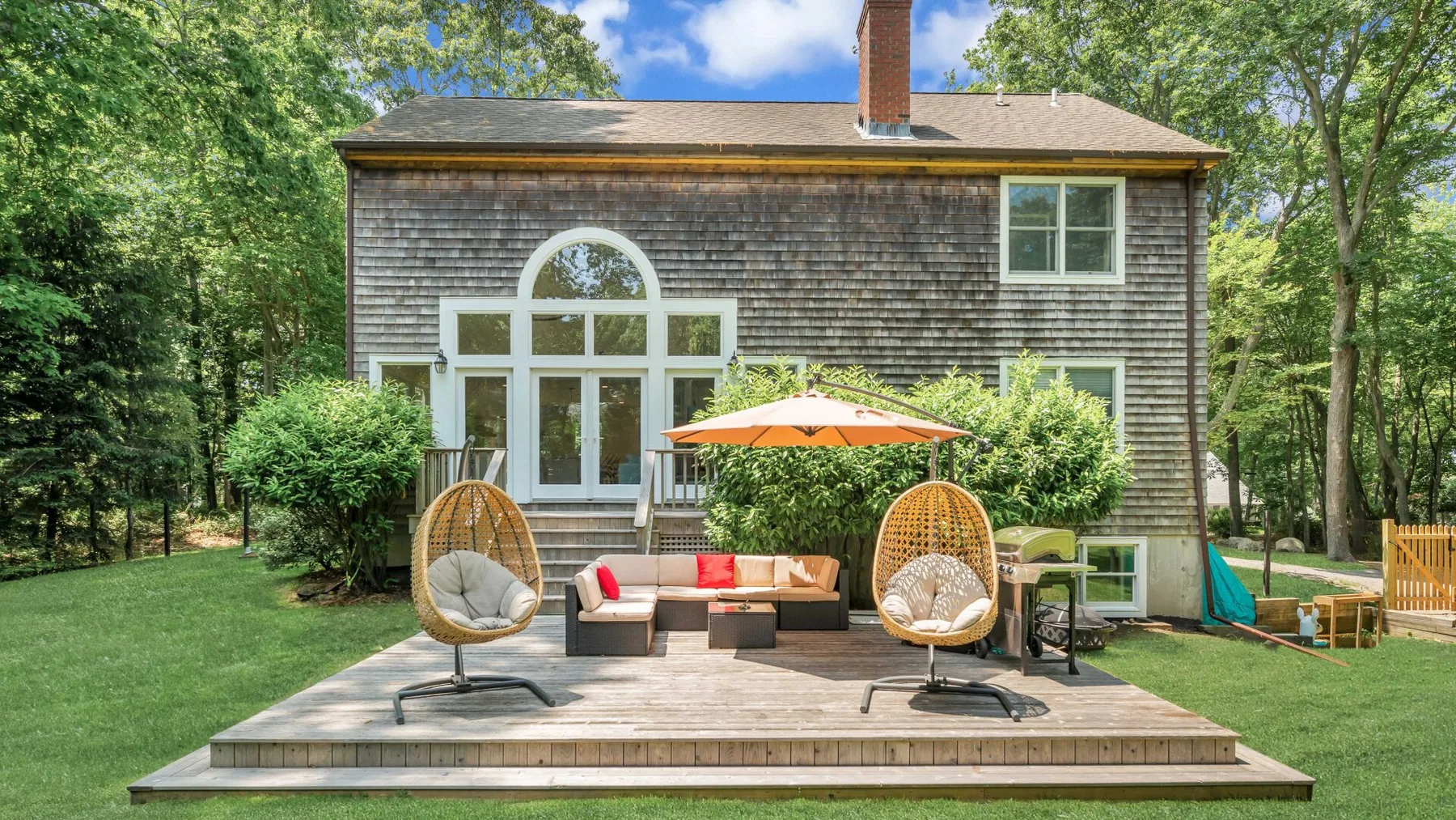 A backyard patio with outdoor seating and a large arched window on the house.