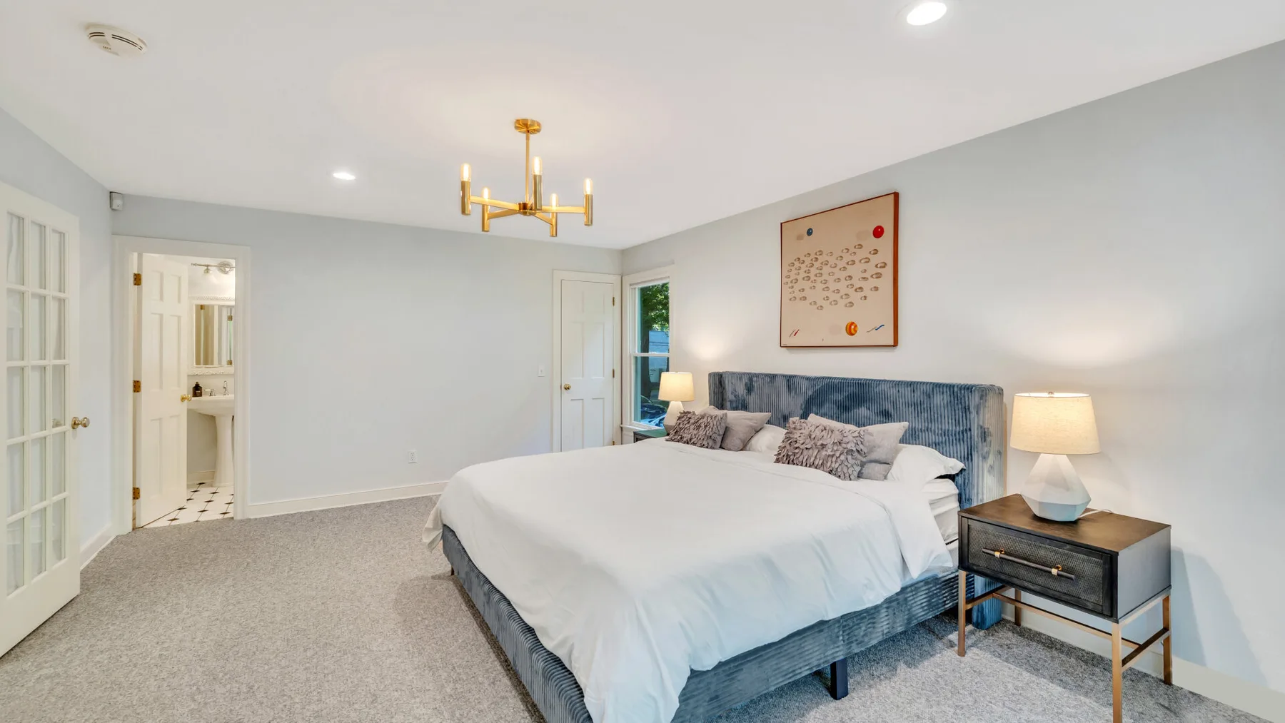 A bedroom with a large bed, bedside table, and doorway to a bathroom.