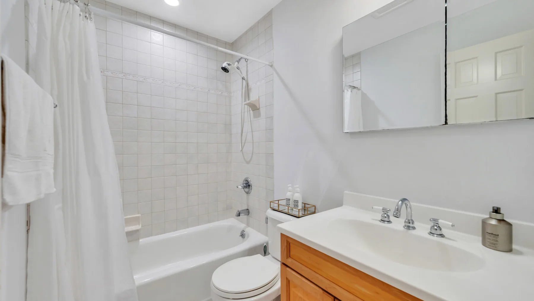 A bathroom with a bathtub, shower curtain, and vanity.