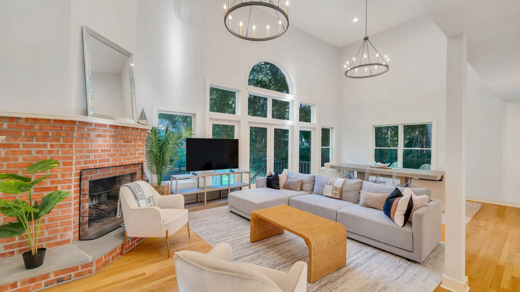 A bright living room with a sectional seating area and tall windows.