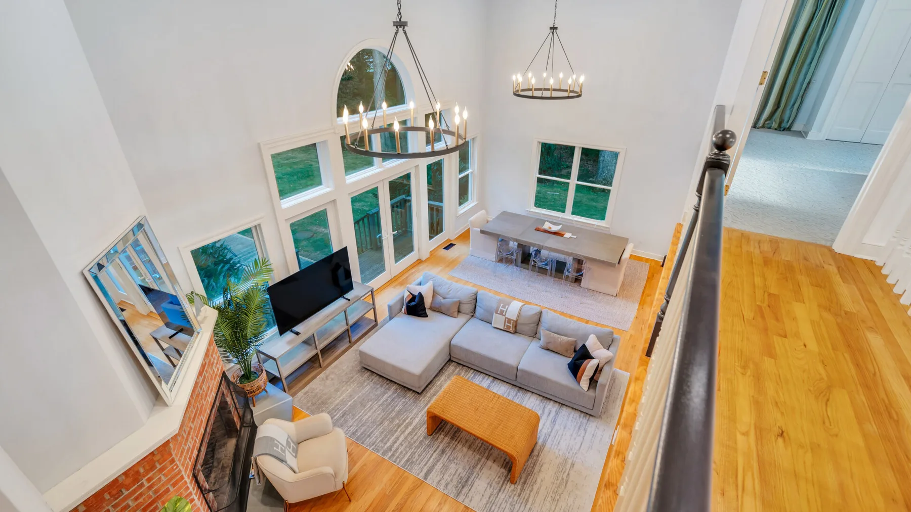 A double-height living room with seating, large windows, and a television.