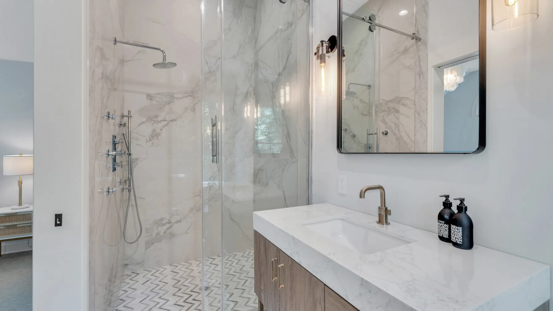 A bright bathroom with a glass shower and a white vanity beneath a large mirror.