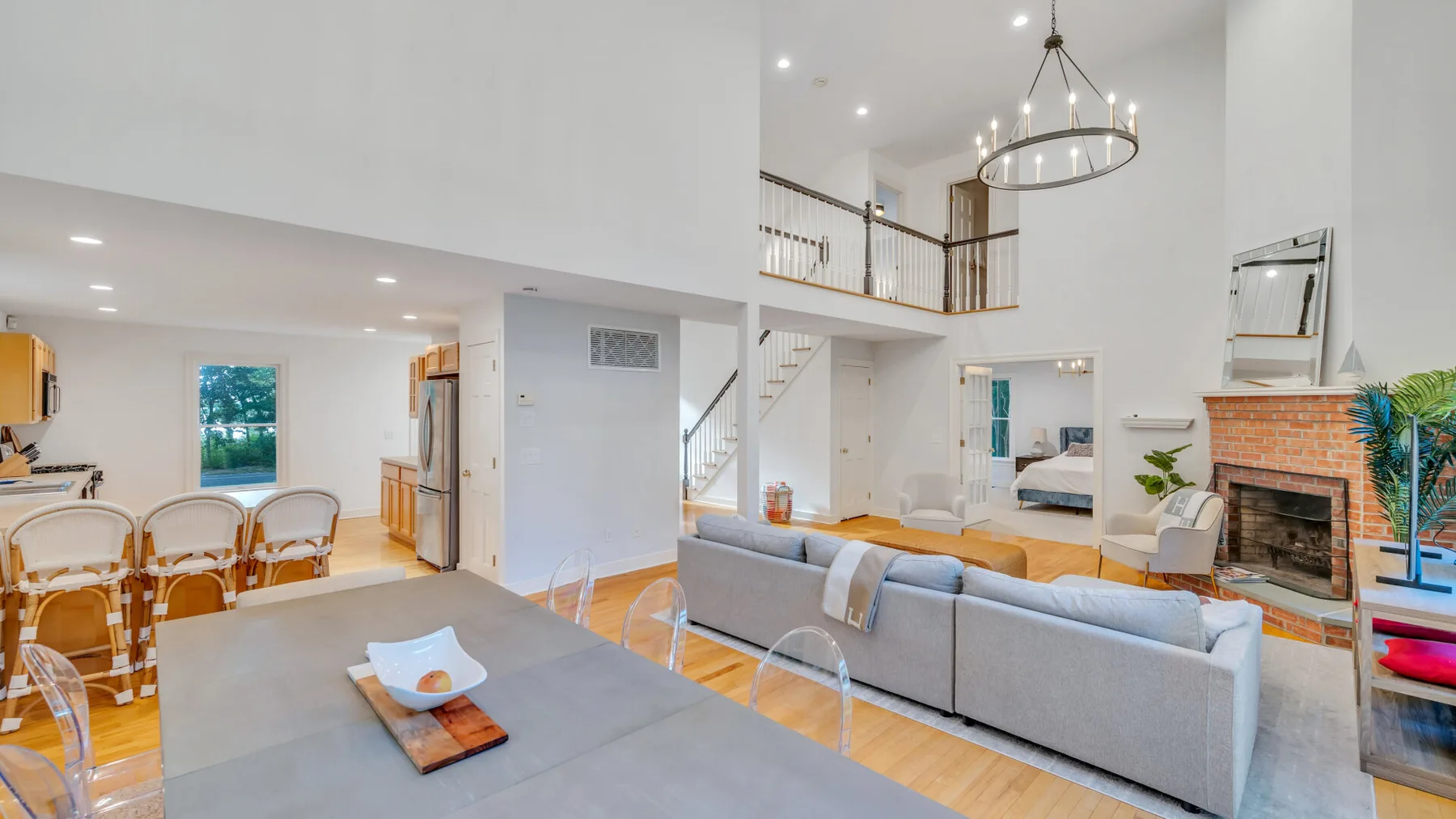 A bright open-plan living and dining area with a high ceiling and fireplace.