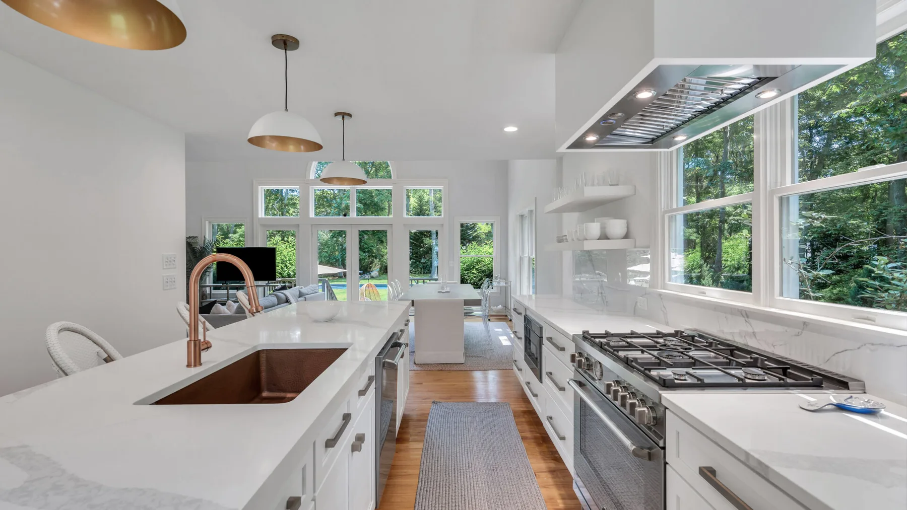 A bright modern kitchen with white counters, a central island, and large windows.