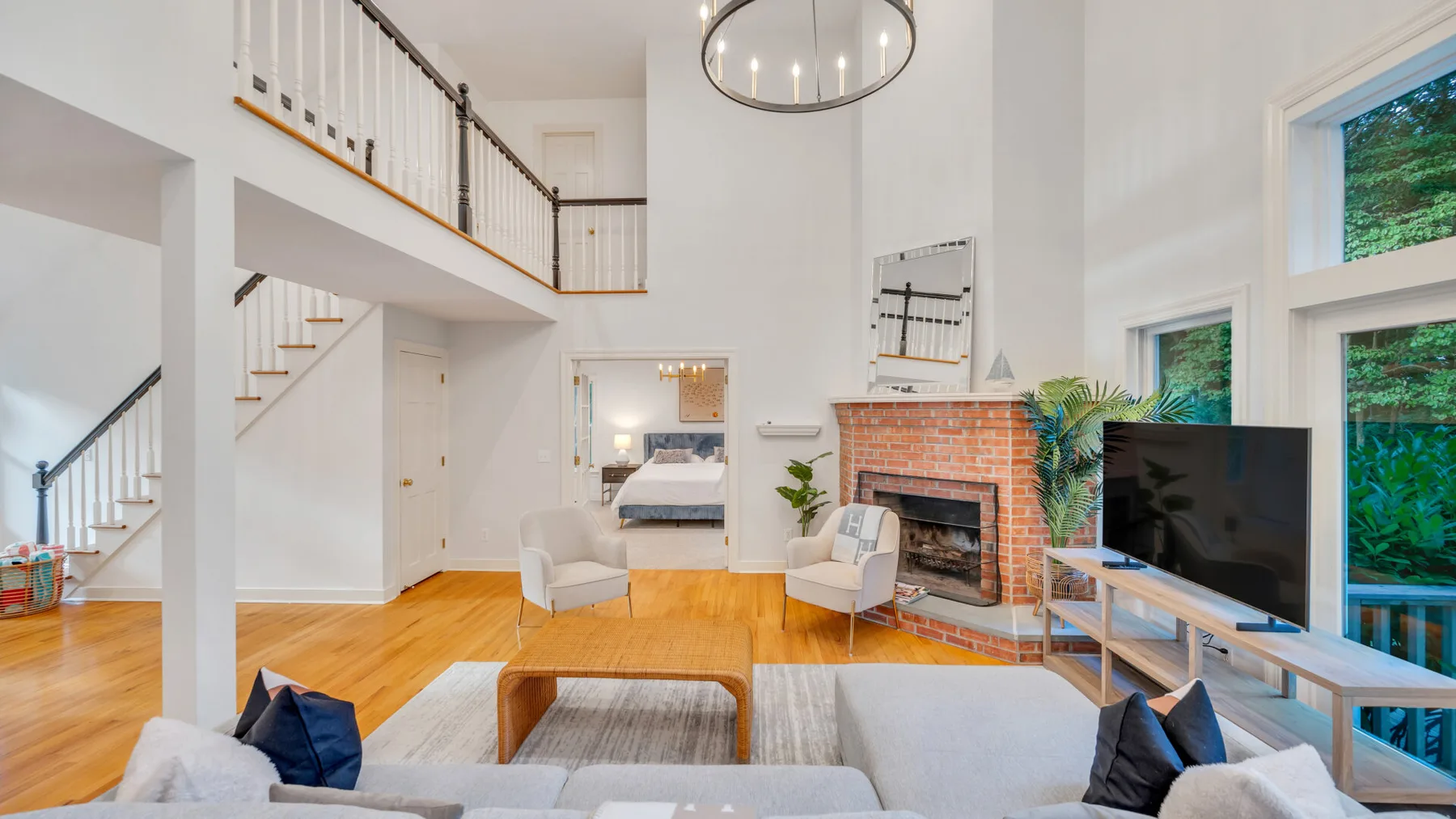 A bright living room with a fireplace, seating, and a staircase.