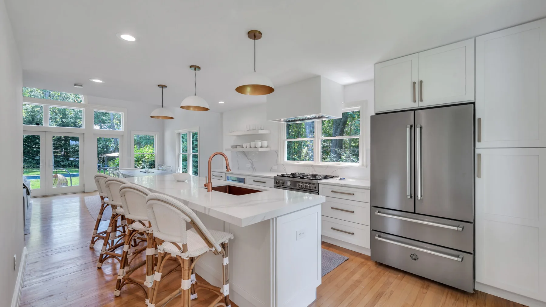 A bright kitchen with a large island and windows overlooking greenery.