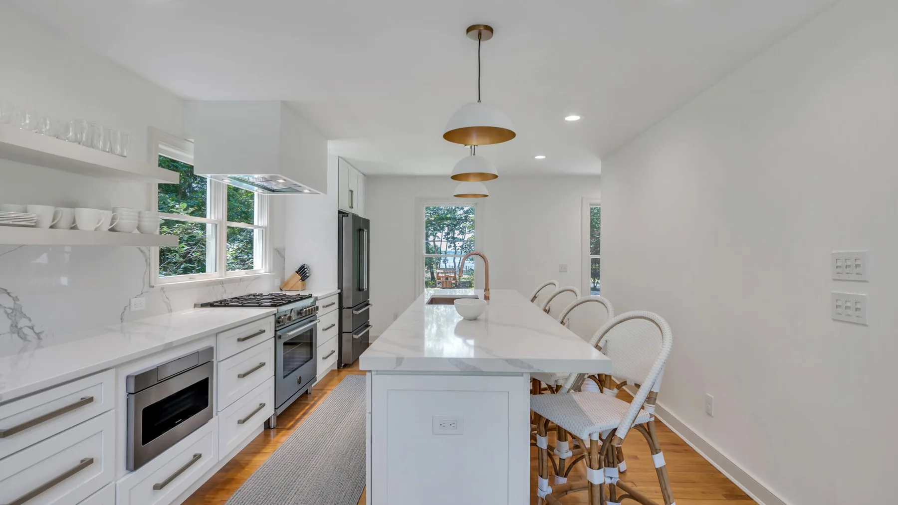 A bright kitchen with a central island, counter seating, and large windows.