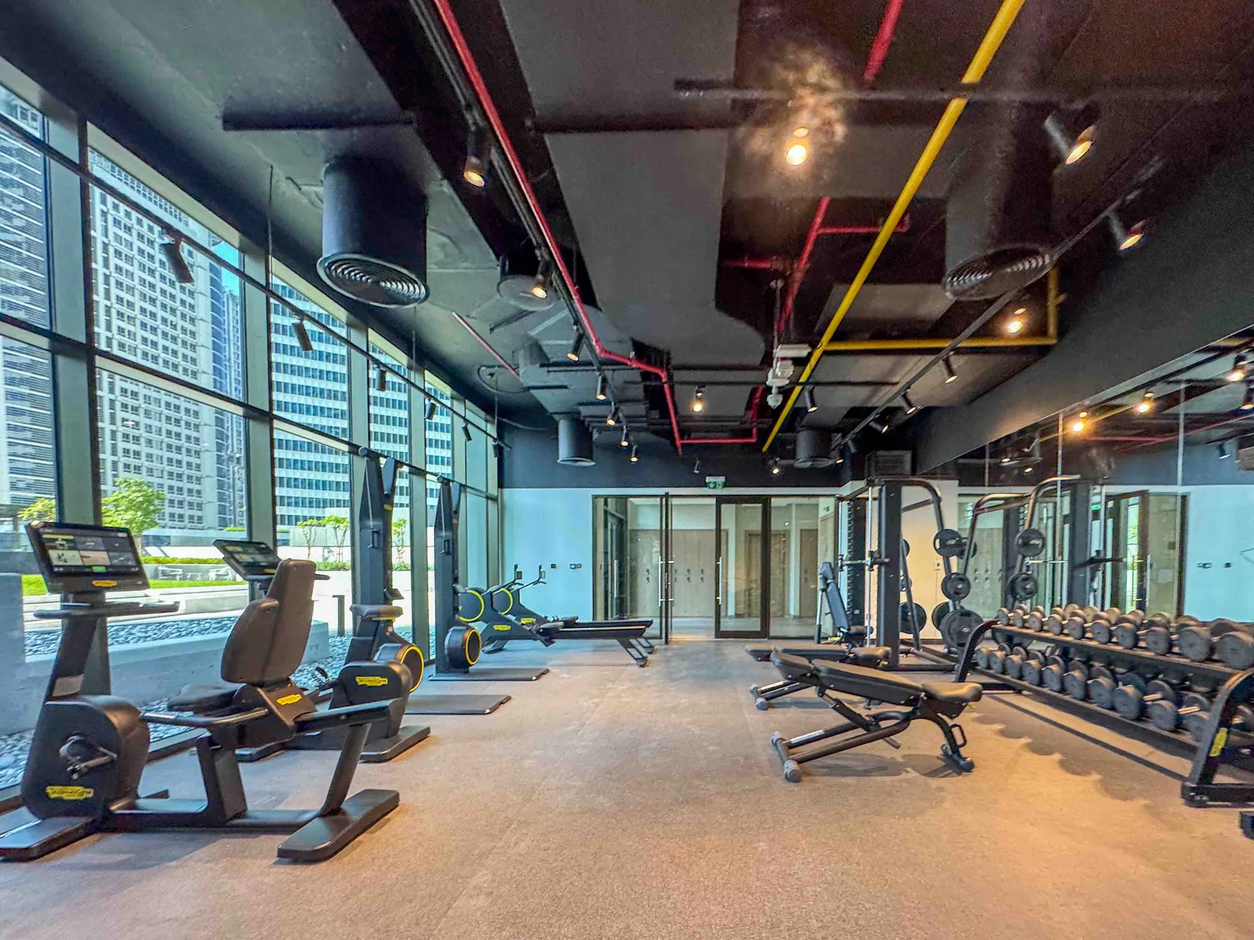 A gym with workout machines, weight benches, and a row of dumbbells.