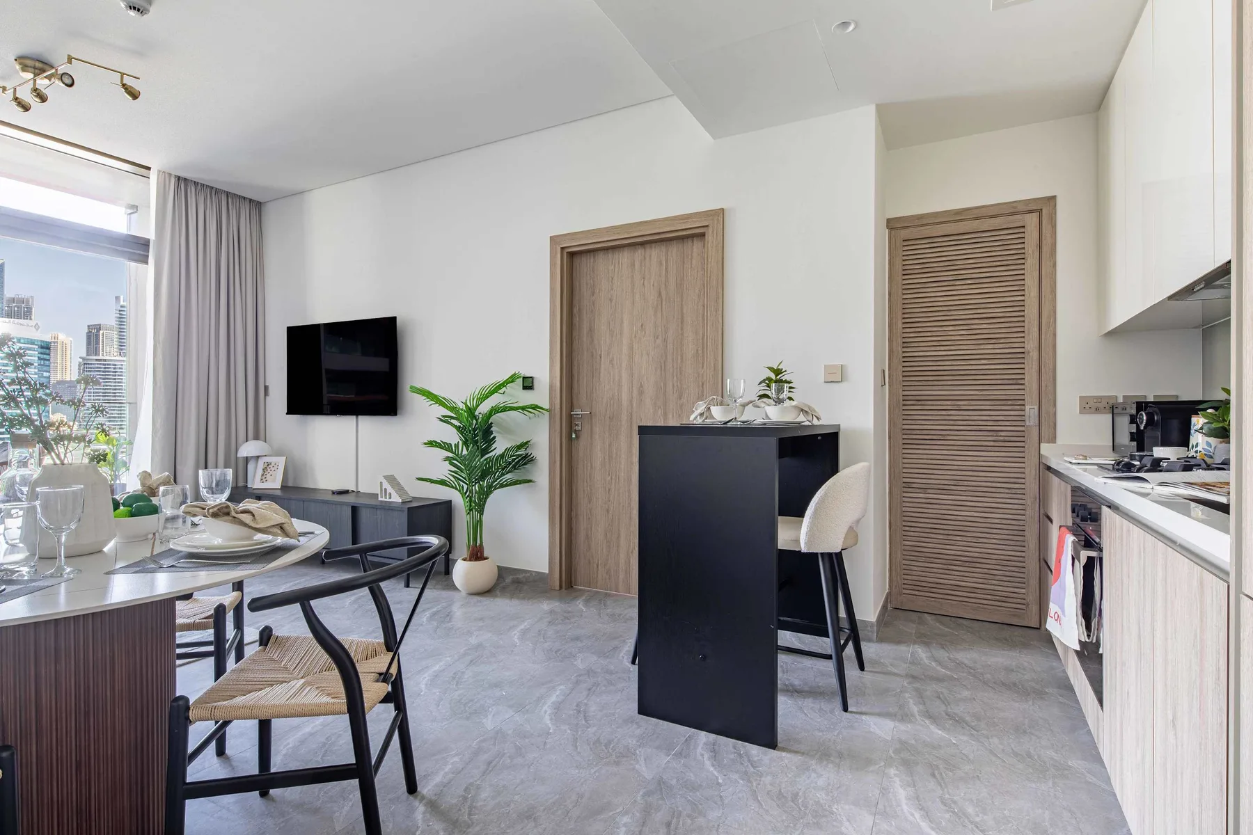 A bright modern kitchen and dining area with a counter and table by the window.
