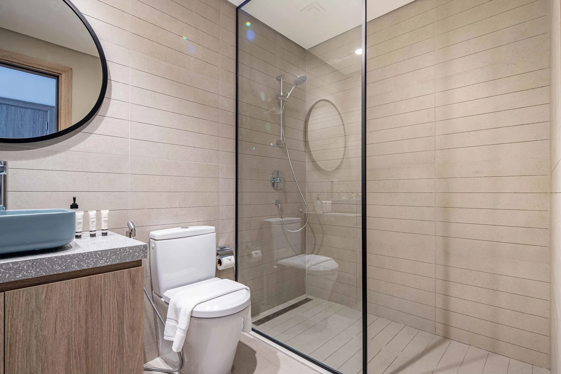 A tiled bathroom with a glass shower, toilet, and sink.