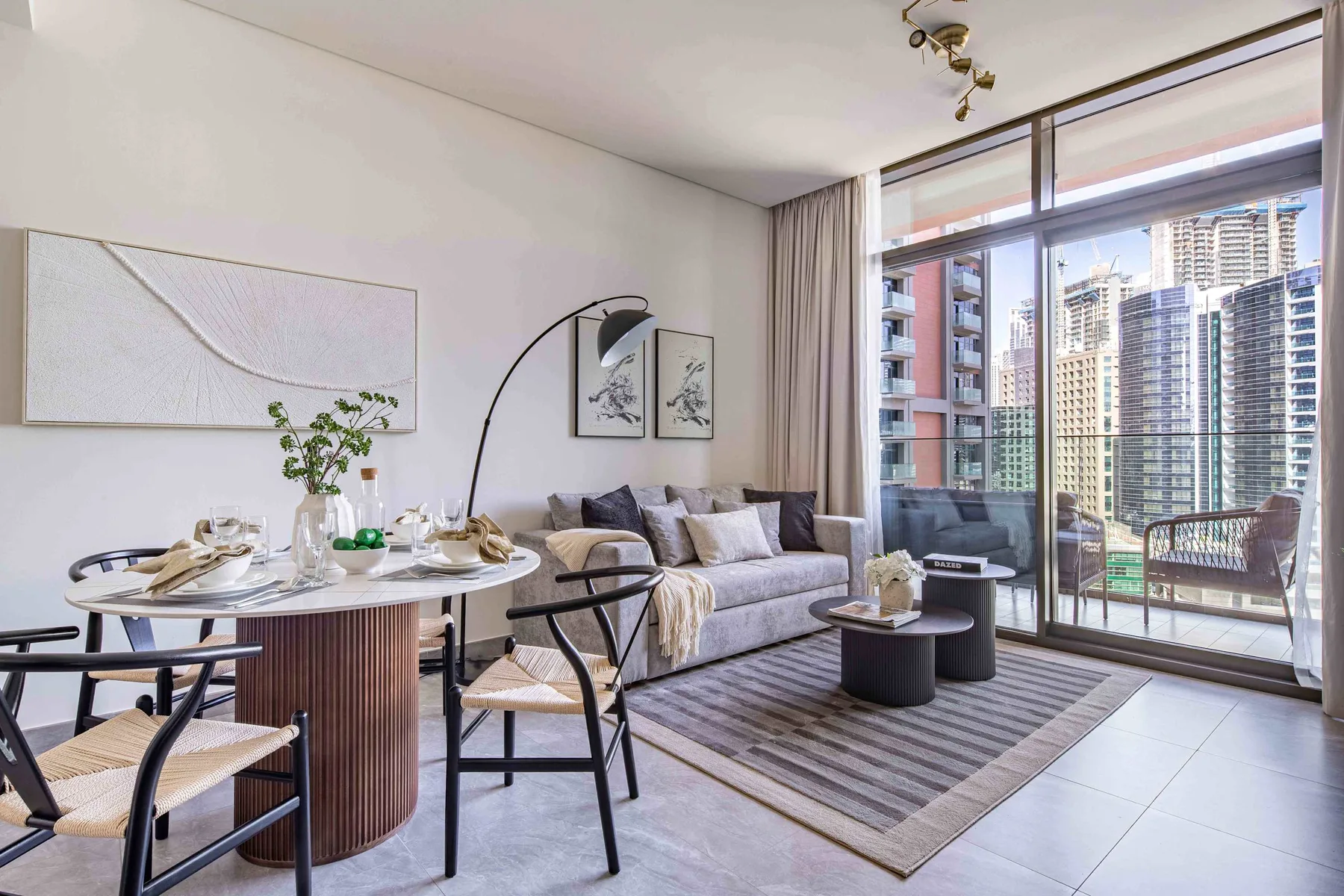 A bright living and dining area with seating beside floor-to-ceiling windows.