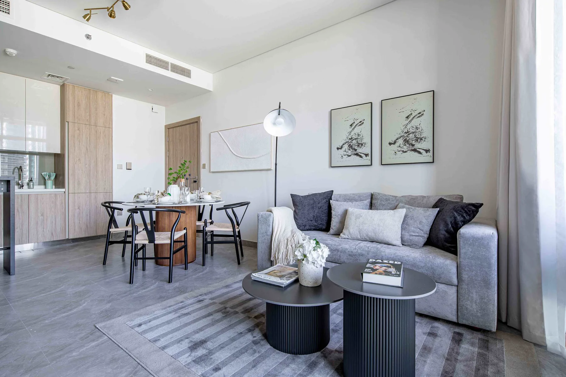 Una zona de sala y comedor con asientos grises, una alfombra y una mesa de comedor.