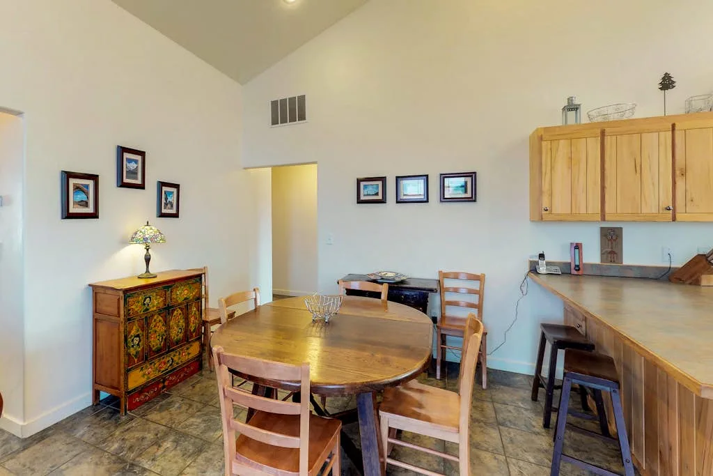 Comedor con una mesa de madera y sillas junto a una barra de cocina.