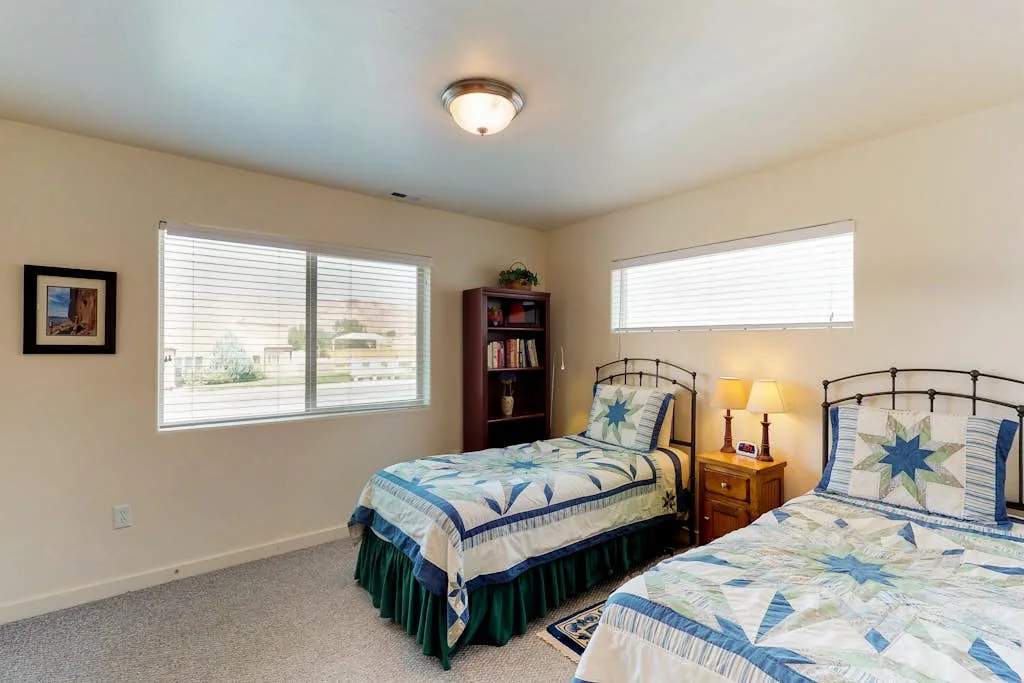 Un dormitorio con dos camas vestidas con ropa de cama estampada en azul y verde.